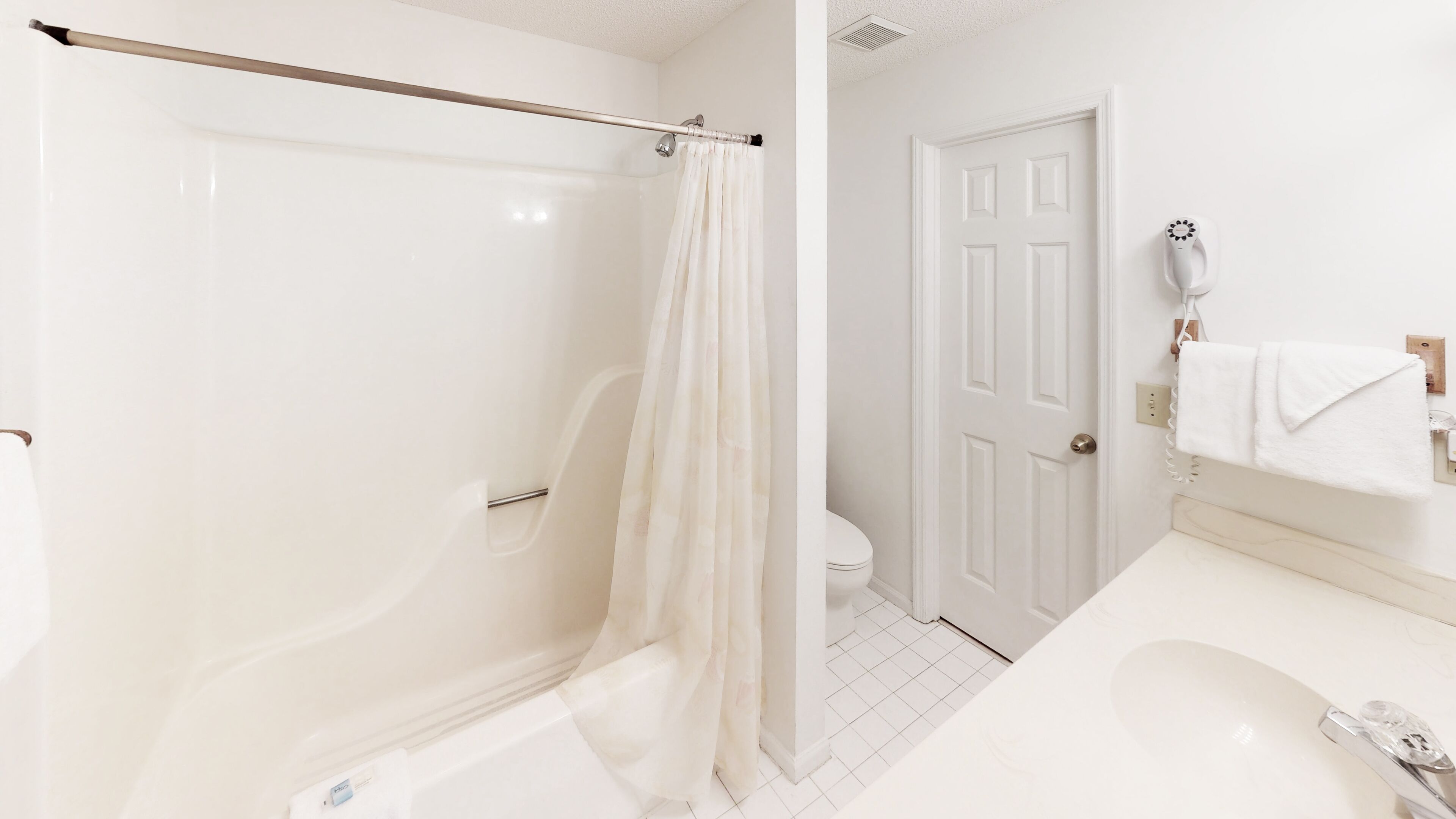 A bathroom with a bathtub, toilet, and shower curtain.