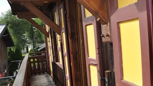 Un balcón de madera con puertas amarillas y rojas, que da a un edificio de estructura de madera.