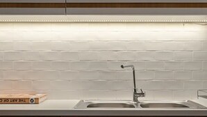 A kitchen with a white brick backsplash, a double sink, and a book titled "The Art of Cooking" on the counter.