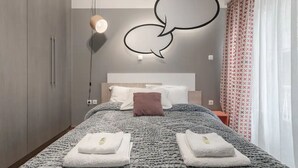 A modern hotel room with a large bed, a wall-mounted light fixture, and a decorative speech bubble design.