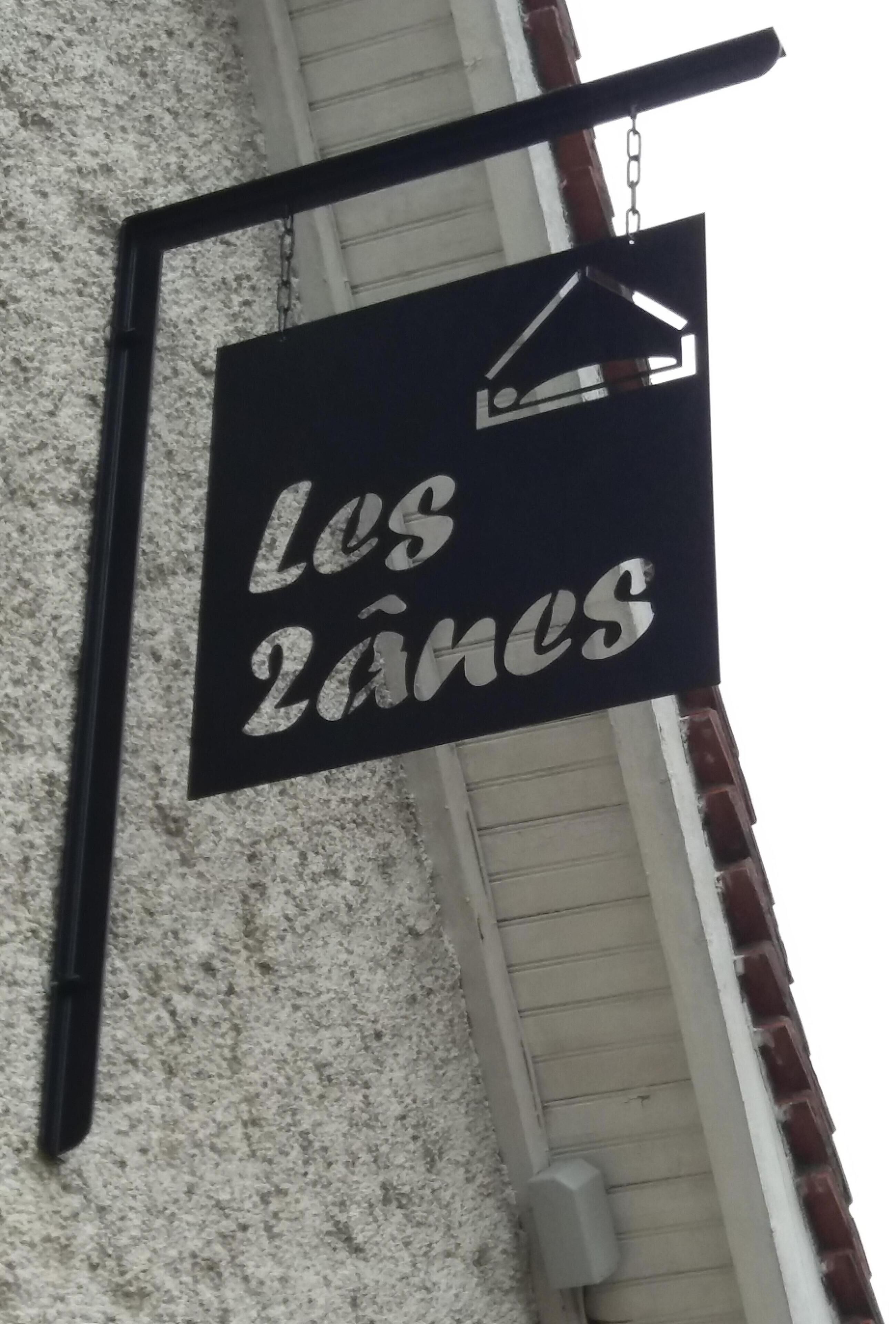 A sign with the text "Los 2 Anes" mounted on a wall.