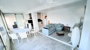 A modern living room with a sectional sofa, a dining table with chairs, a kitchen area, and a laundry room.