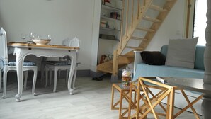 Ein Wohnzimmer mit Esstisch, Stühlen, einer Treppe, einem Sofa und einem Bücherregal.