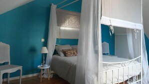 Ein Schlafzimmer mit einem Bett unter einem Baldachin, einem Nachttisch, einer Lampe und einem Sessel.