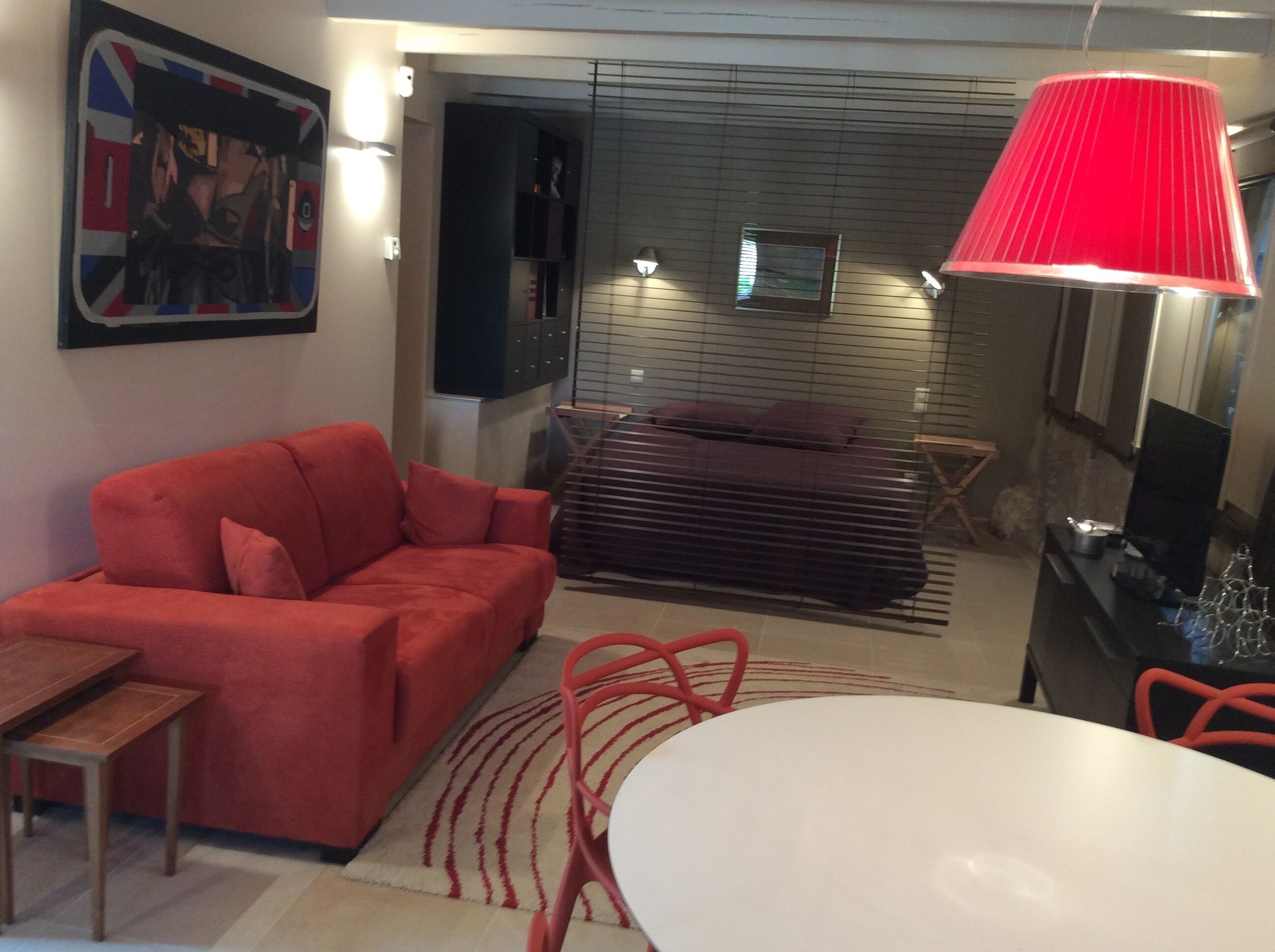 A modern living room with a red sofa, a white table, and a red lamp.