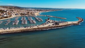 An aerial view of a marina with numerous boats docked, a sandy beach, and a rocky breakwater. - La Rosa dei Venti - Typical, Independent with Exclusive Terrace at150 mt from the Sea (Marina di Ragusa)