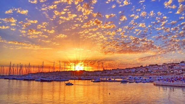 A marina with boats docked, a sunset in the background, and a town across the water. - La Rosa dei Venti - Typical, Independent with Exclusive Terrace at150 mt from the Sea (Marina di Ragusa)
