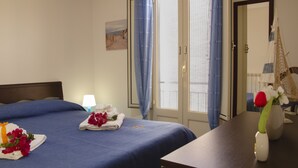 A hotel room with a neatly made bed, a bedside table with a vase of flowers, and a view through the door. - La Rosa dei Venti - Typical, Independent with Exclusive Terrace at150 mt from the Sea (Marina di Ragusa)
