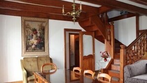 Un comedor con mesa y sillas de madera, un candelabro y una escalera que sube a otro nivel.