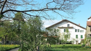 Entorno rural con una casa blanca, un camino de grava y campos verdes.