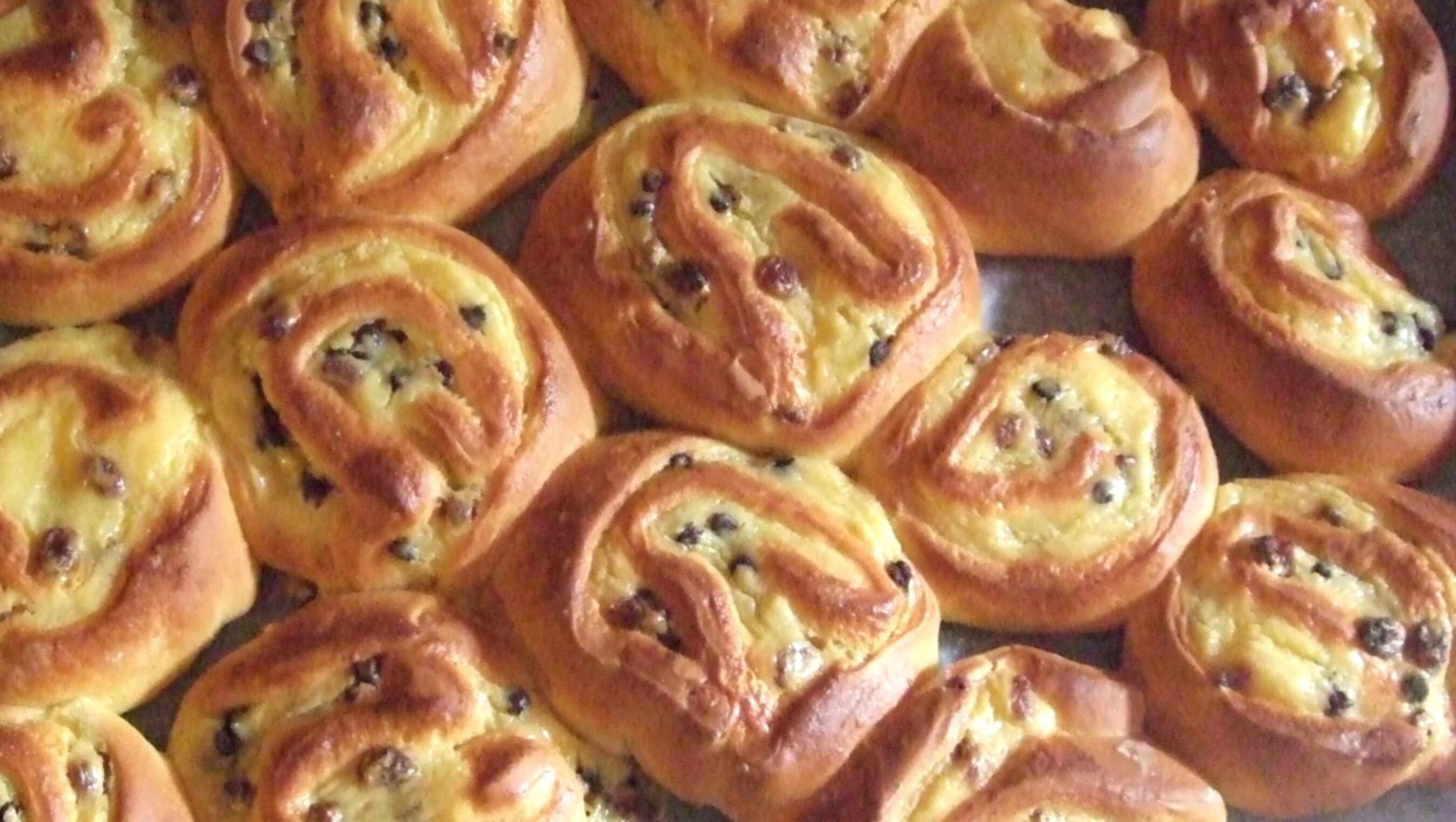 A tray of freshly baked pastries with a golden-brown crust and visible fruit pieces.
