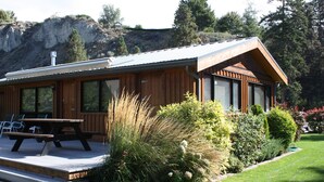 Eine Holzhütte mit einer Terrasse, großen Fenstern und Bergblick.