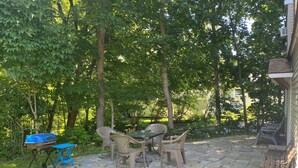 An outdoor patio with a table and chairs, surrounded by trees.