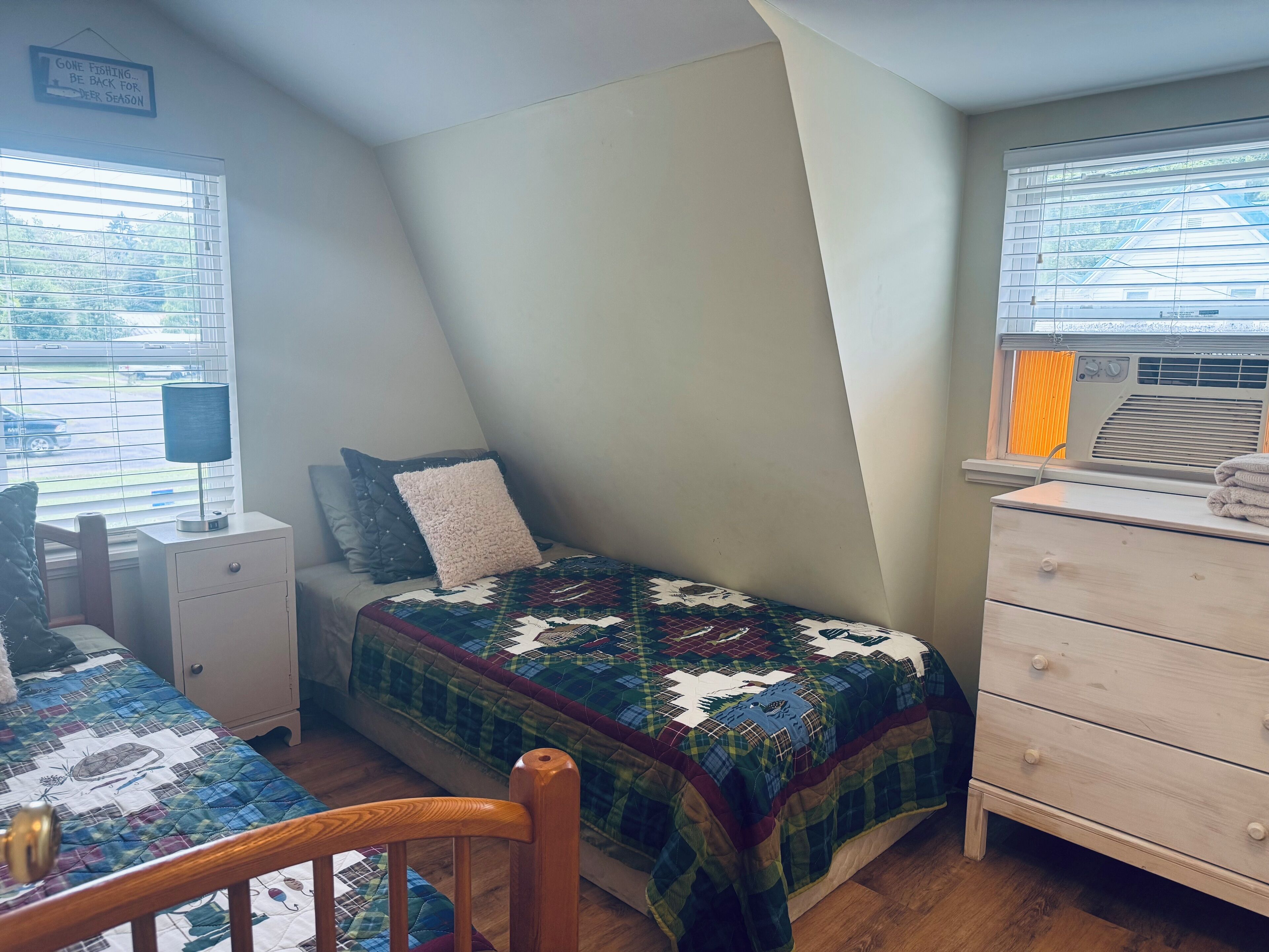 A bedroom with a bed, a nightstand, a dresser, and a window with blinds.