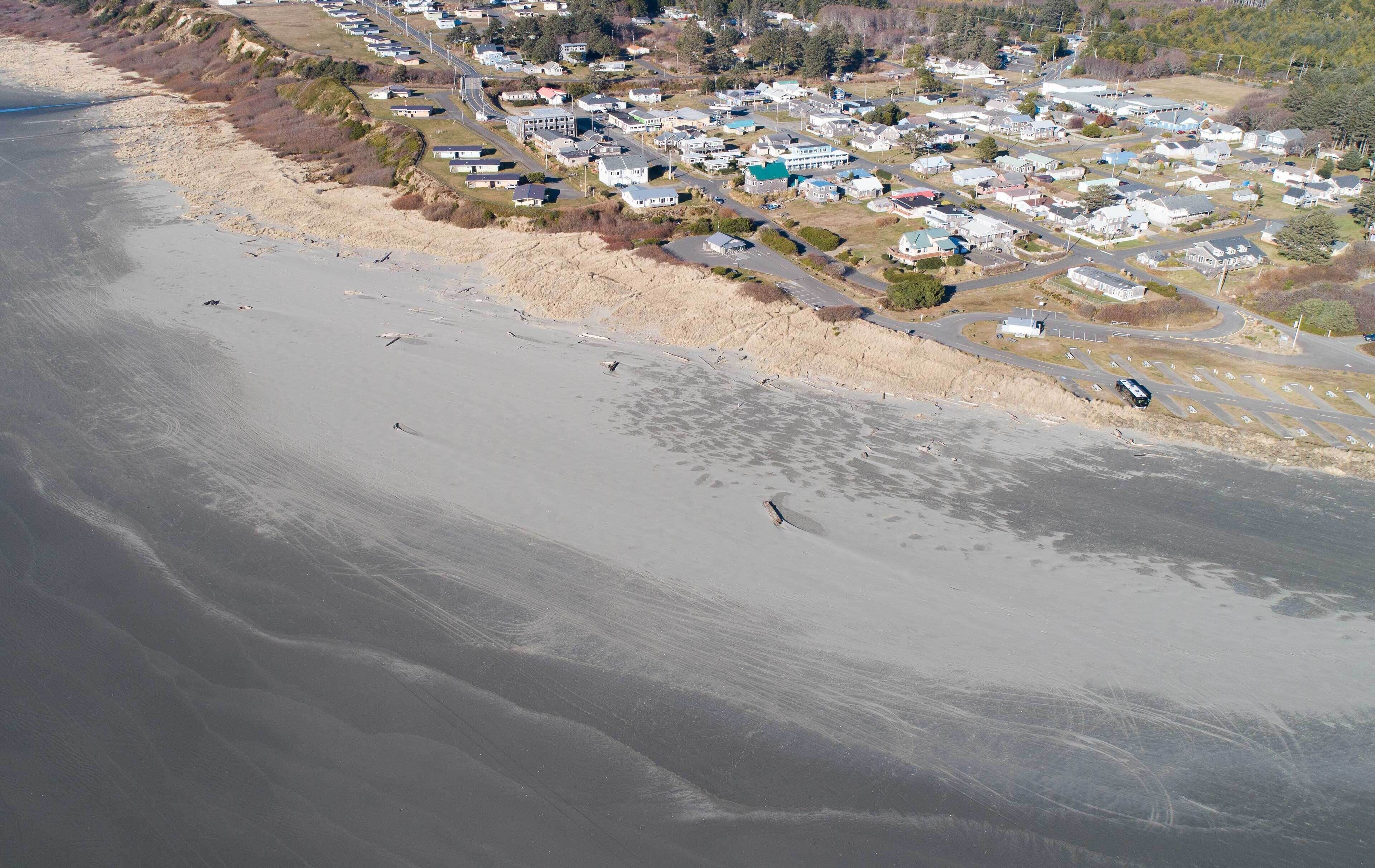 Vista aérea de una zona residencial costera con casas, carreteras y una playa.