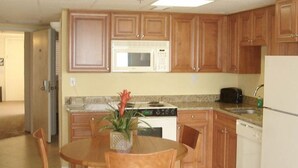 A kitchen with wooden cabinets, a microwave, a stove, and a refrigerator. - Gorgeous Oceanview Condo (Ormond Beach)