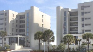 A modern multi-story residential building with balconies and palm trees in the foreground. - Gorgeous Oceanview Condo (Ormond Beach)
