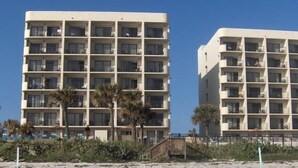 Two multi-story buildings with balconies, located near a beach. - Gorgeous Oceanview Condo (Ormond Beach)