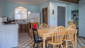 Une cuisine compacte avec un coin repas, comprenant une table et des chaises en bois, un réfrigérateur et une cuisinière.