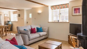 A cozy living room with a sofa, a television, and a fireplace. - Cottage 1 - sleeps 4 guests  in 2 bedrooms (New Yatt)