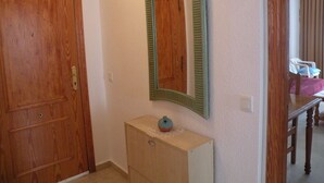 Ein Flur mit einer Holztür, einem kleinen Holzkabinett und einem Spiegel an der Wand.