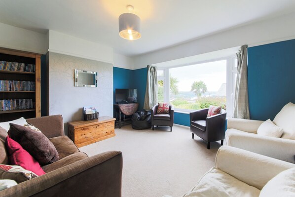 A living room with a bookshelf, a TV, a wooden chest, and two sofas.
