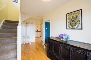 A staircase leading to a room with a wooden floor, a white door, and a blue wall.