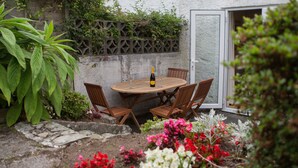 Een houten tafel met stoelen, een fles wijn en een glas in het midden.