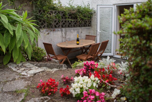 A wooden table with chairs, a bottle of wine, and a glass in the center.