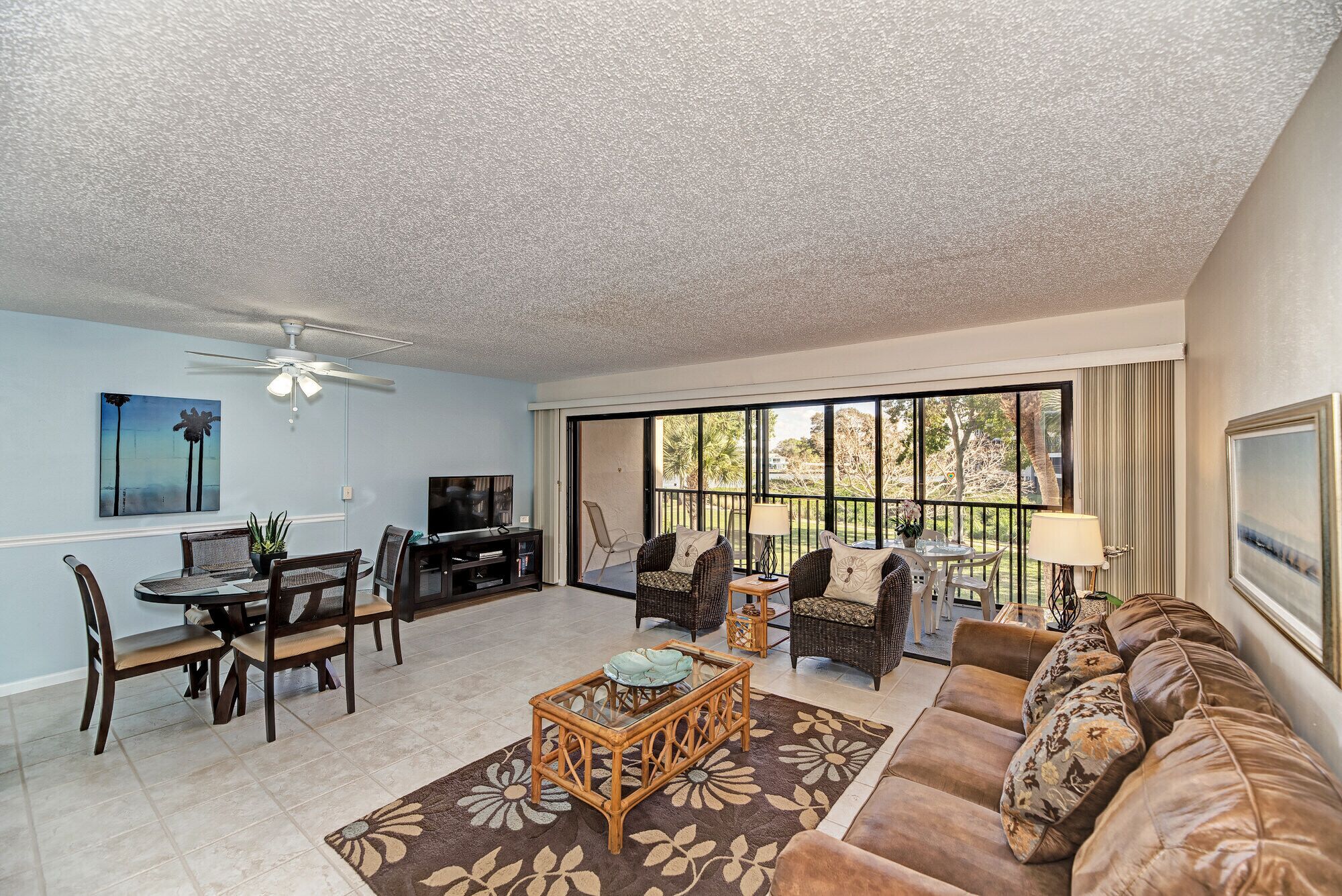 A living room with a dining area, a TV, and a large window with a view of trees.