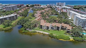 An aerial view of a coastal resort area with multiple buildings, a marina, and a river. - Beautiful Siesta Key Condo (Siesta Key)