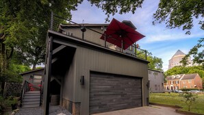 A modern building with a garage door, a staircase, and a red umbrella. - Charlotte Cityscape Studio, Huge Deck, Stunning View (Charlotte)