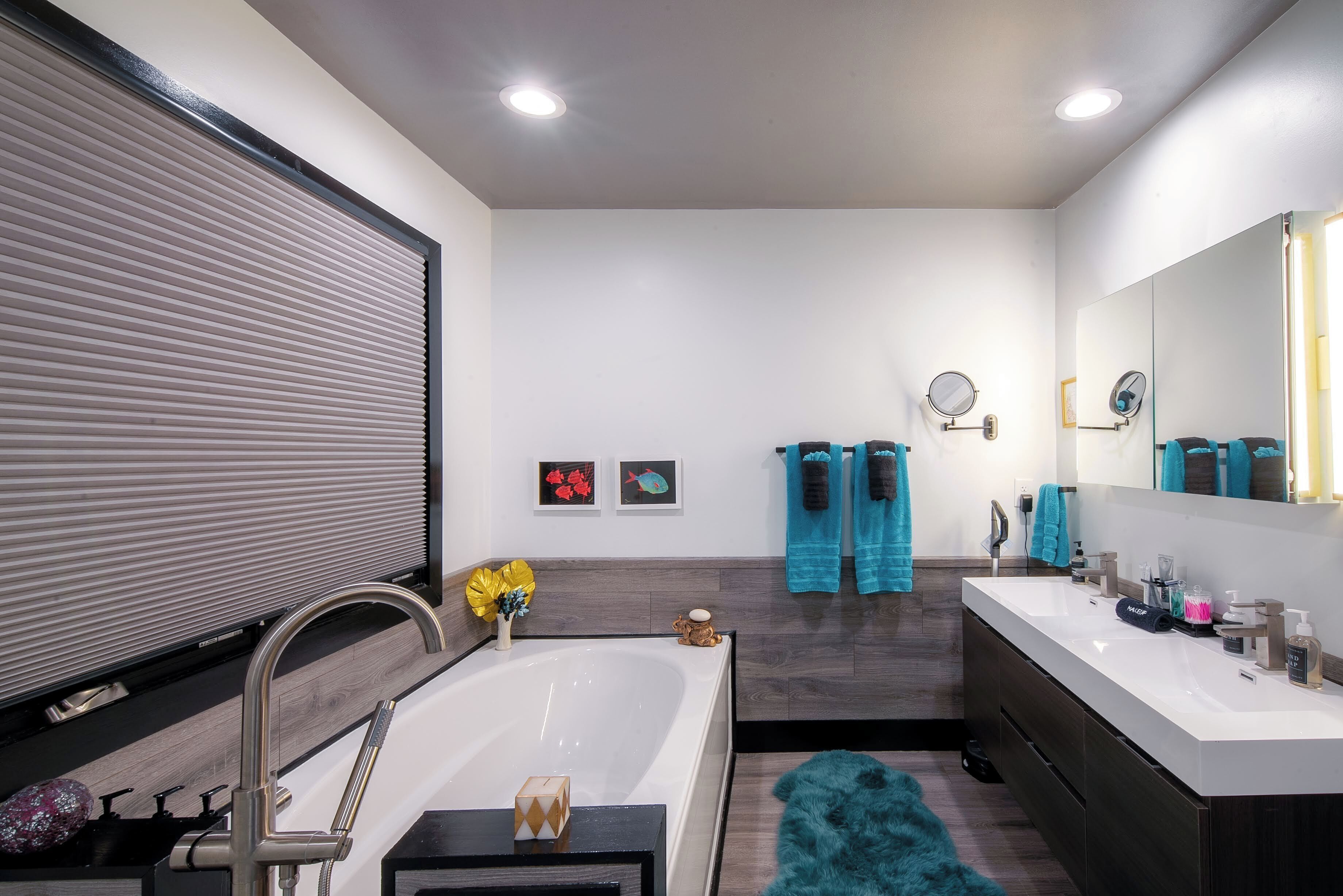 A modern bathroom with a large bathtub, two sinks, and a mirror.