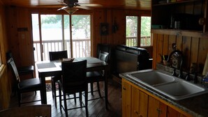 Una cabaña de madera con comedor, cocina y terraza.