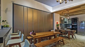A modern dining area with a wooden table and benches, a kitchen in the background, and a sliding door separating the dining area from another space. - Wujie Childlike B&B (Wujie)