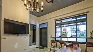 A modern dining area with a wooden table, chairs, a chandelier, and a large window with a city view. - Wujie Childlike B&B (Wujie)