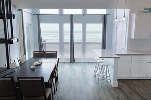 Eine moderne Küche mit Meerblick, ein Essbereich mit Stühlen und ein Barhocker.