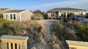 Um imóvel à beira-mar com duas casas, um caminho de areia e estruturas de deck de madeira.