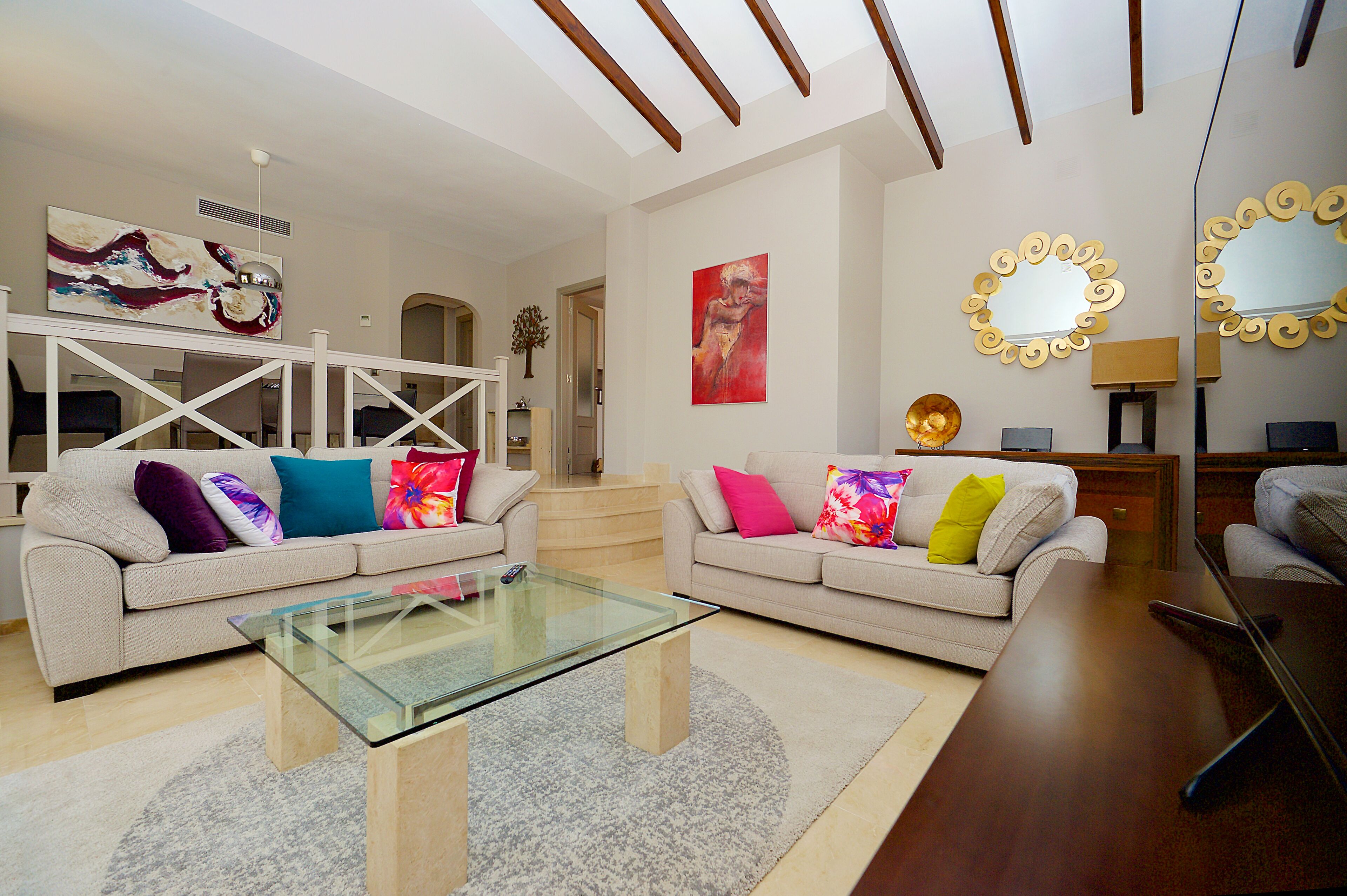 A modern living room with two sofas, a glass coffee table, and a wooden side table.