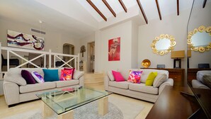 Una sala de estar moderna con dos sofás, una mesa de centro de vidrio y una mesita auxiliar de madera.