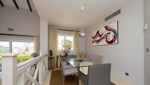 Un comedor con una mesa de vidrio, sillas y vistas al exterior.