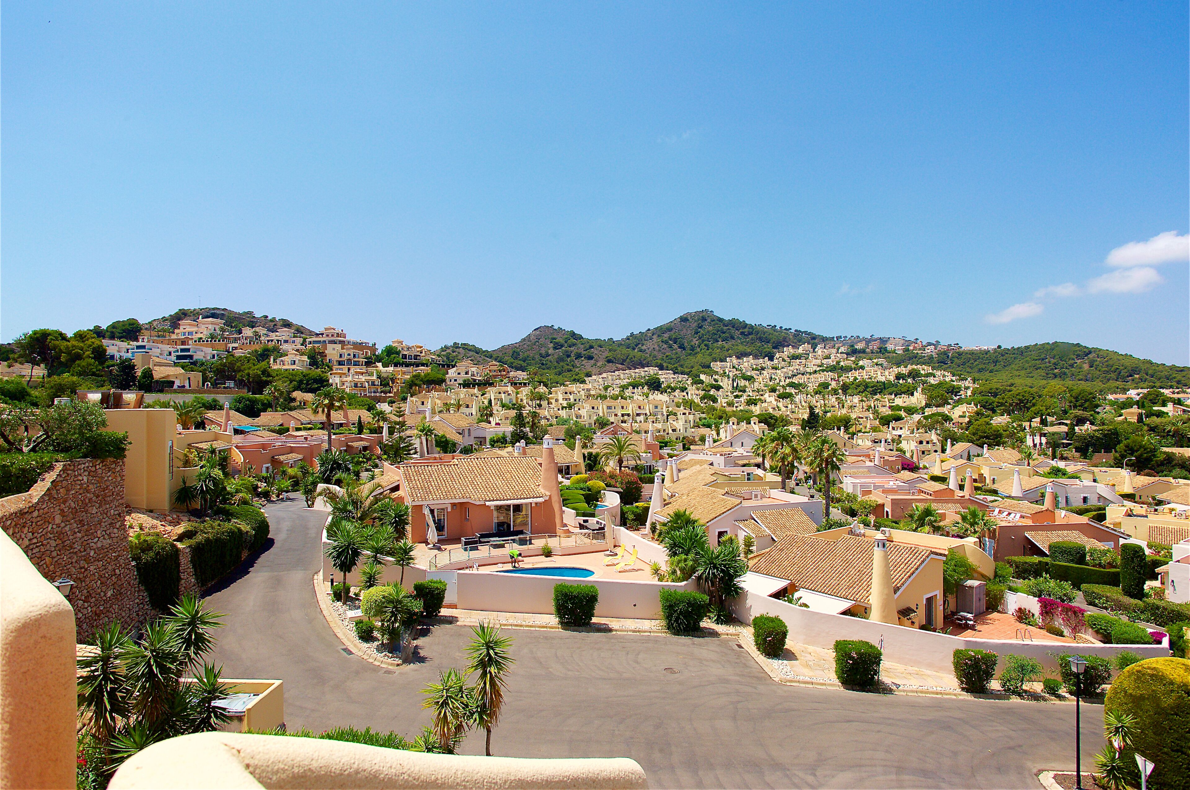 A residential area with houses, a swimming pool, and a hilly backdrop.