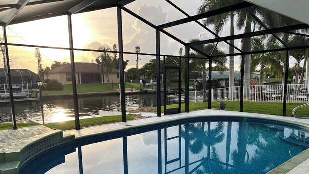 Piscina interna com vista desimpedida para o pôr do sol e um corpo d'água lá fora.