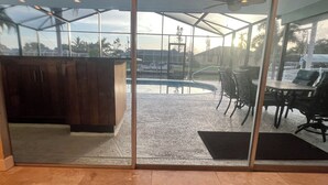Um alpendre envidraçado com piscina, móveis de exterior e ventoinha.