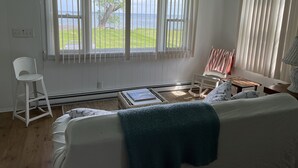 A room with a bed, a chair, a table, and a view of the outdoors.
