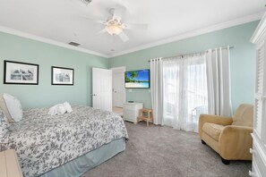 Un dormitorio con cama, una silla, un escritorio y una televisión.