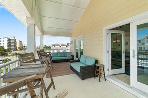 Un espacio al aire libre techado con muebles de madera, un sofá de mimbre y un taburete pequeño.