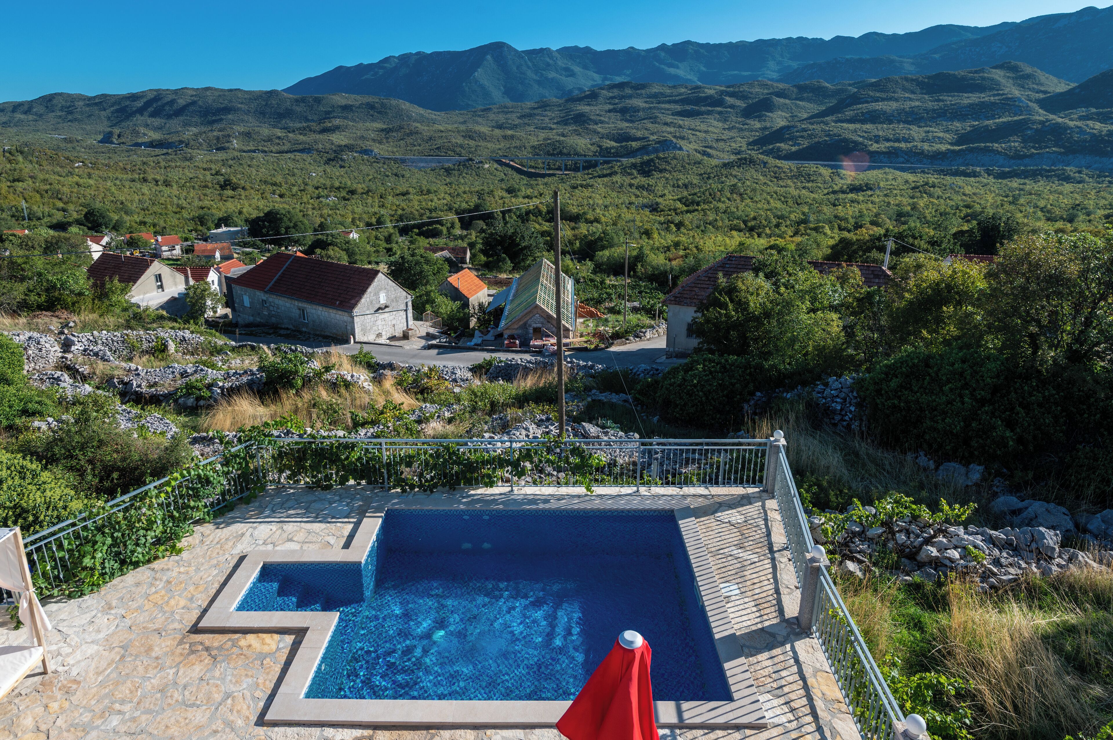 A pool area with a view of a village and mountains.