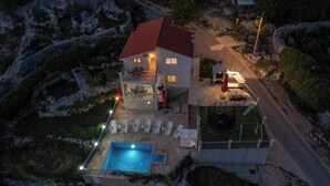 A two-story house with a swimming pool, outdoor seating, and a red-roofed structure. - Holiday house Marijana (Zagvozd)