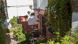Un patio con un edificio blanco, un barril de madera y plantas en macetas.